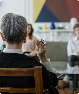 A woman sitting in a chair, resting her chin on her hand, appears thoughtful and contemplative.